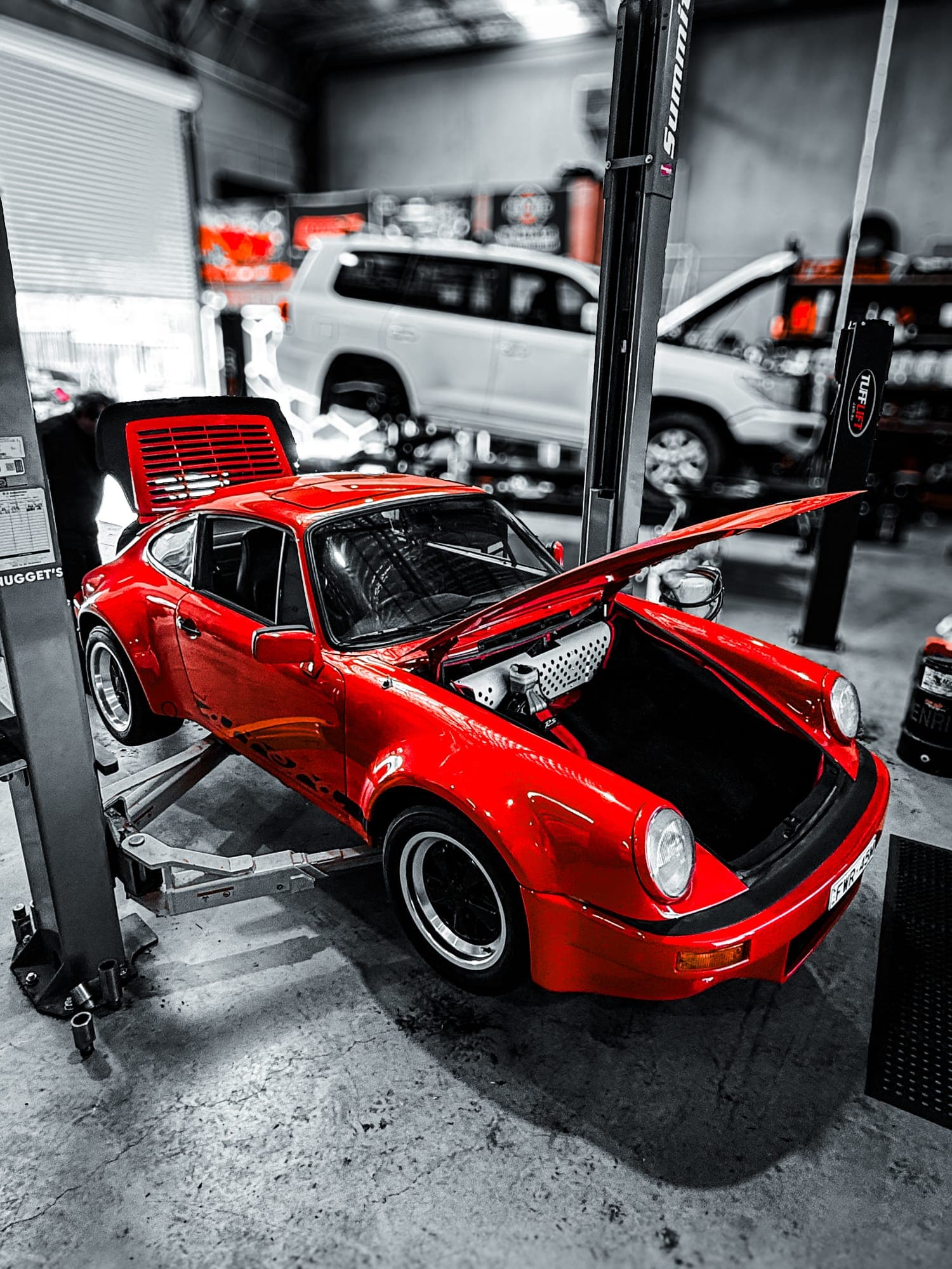Classic red Porsche 911 with whale tail on the hoist for service